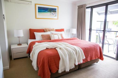 努萨维尔Tropical Getaway in 2 Bedroom Unit in 4 star Resort的一间卧室配有一张带橙色毯子的床