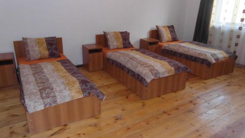 KhashuriGvirilas Sakhli Guest House的铺有木地板的客房内的三张床