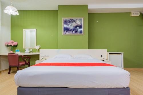 新山HOTEL 101 PERMAS JAYA的一间卧室设有一张带绿色墙壁的大床
