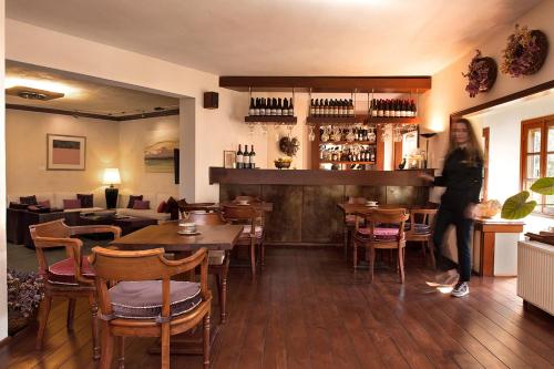 美特索文Katogi Averoff Hotel & Winery的站在带桌椅的餐厅的妇女