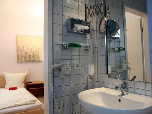 杜塞尔多夫卡萨别墅酒店的一间带水槽和镜子的浴室以及一张床
