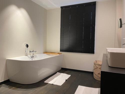 布鲁日Guesthouse next Do的白色的浴室设有浴缸和水槽。
