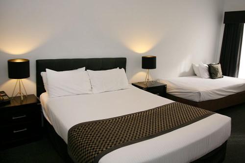 墨尔本福特斯克瑞汽车旅馆加服务式公寓酒店的酒店客房设有两张床和两盏灯。