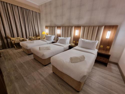 迪拜Vista Square Hotel的酒店客房设有三张床和一张桌子