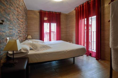 托莱多托莱多旅游公寓的一间卧室配有床和两个带红色窗帘的窗户。