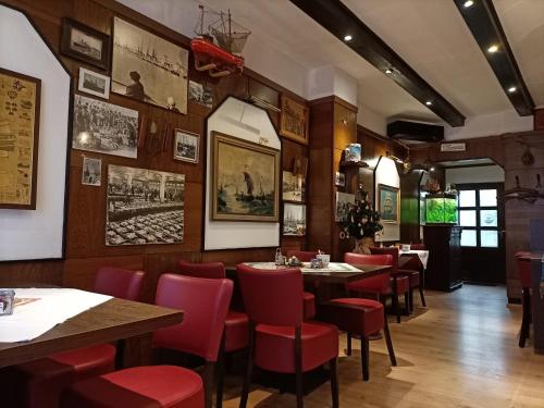 不来梅港安德尔卡尔施塔特酒店的用餐室配有桌子和红色椅子
