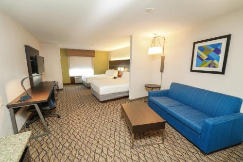 斯普林菲尔德斯普林菲尔德医疗区快捷假日&套房酒店的酒店客房配有蓝色的沙发和床。