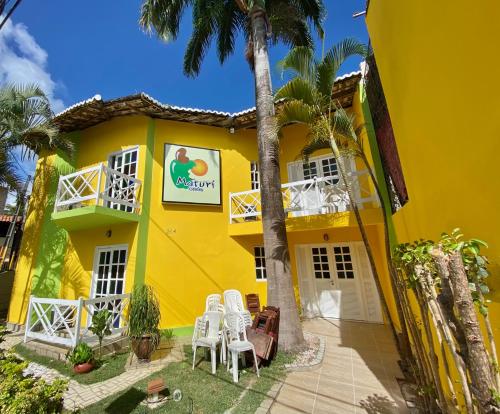 皮帕MATURI CENTRO的黄色房子,配有白色椅子和棕榈树
