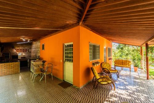 三玛丽亚镇Pousada e Restaurante Maria das Flores的橙色房子的房间,配有椅子和桌子