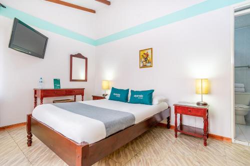 波帕扬Hotel Puerta del Sol Popayan的一间卧室设有一张床、一个卫生间和一台电视。