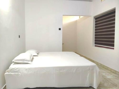 马拉普兰Thekkumpuram Tourist Home的白色的卧室设有白色的床和窗户。
