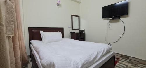 加德满都Pashupati View Hotel的卧室配有白色的床和平面电视。