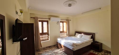 加德满都Pashupati View Hotel的一间卧室设有一张床、一台电视和窗户。