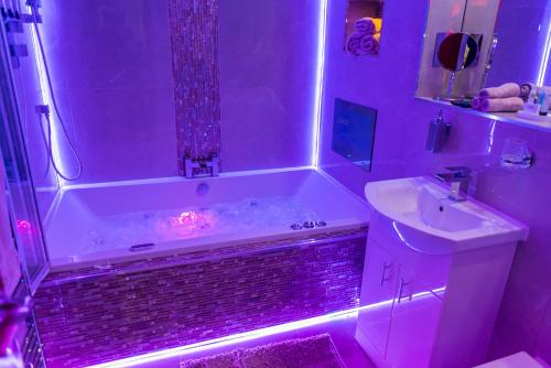 布雷得佛Meridian Serviced Apartments的带浴缸和紫色灯水槽的浴室