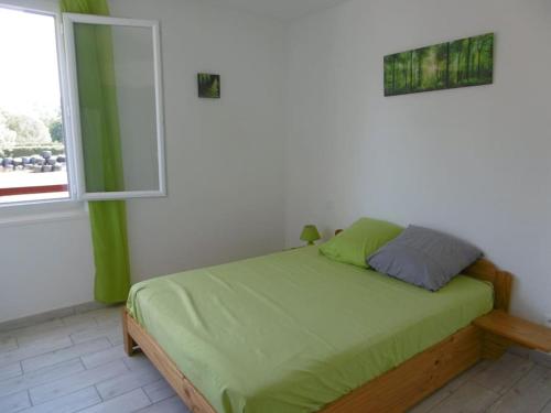 Uhart-Cizebaratzean的一间卧室配有一张带绿色床单的床和一扇窗户。