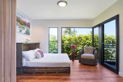 WailuaLuxury 2-Story Oceanfront Condo w/ Views & Pool的一间卧室配有一张床、一把椅子和窗户。