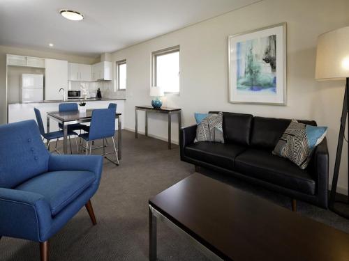 珀斯Baileys Serviced Apartments的带沙发和椅子的客厅以及厨房。