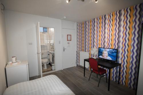 阿姆斯特丹Hotel & bar Royal taste Amsterdam的客房设有一张床、一张书桌和电视