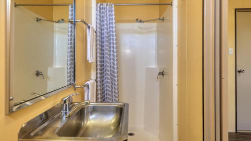 埃默拉尔德Emerald Tourist Park的一间带不锈钢盥洗盆和淋浴的浴室