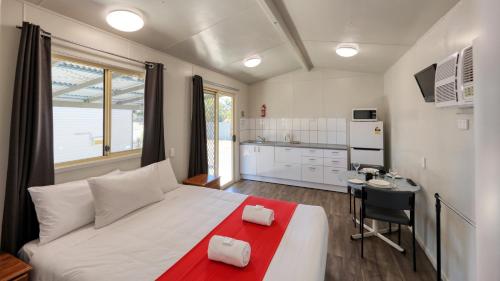 埃默拉尔德Emerald Tourist Park的一间带白色大床的卧室和一间厨房