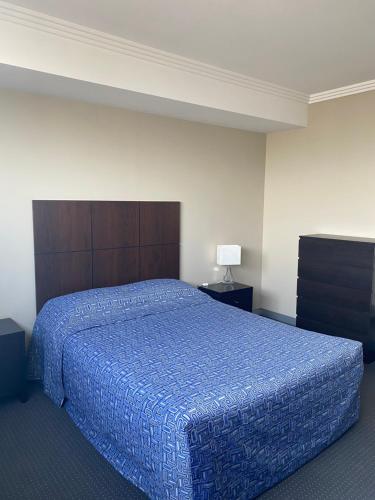 悉尼The Bexley Motel的一间卧室配有一张带蓝色棉被的大床