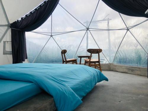 金塔马尼Kubah Bali Glamping的一间卧室配有一张床,帐篷内配有两把椅子