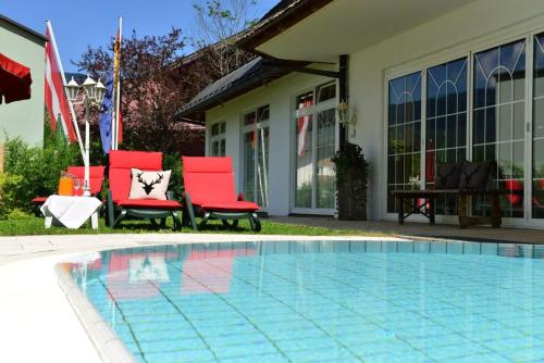 里茨勒恩加戈霍夫酒店的一座房子旁的游泳池,配有两把红色椅子