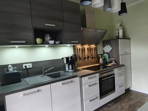 塔勒Ferienwohnung ODIN, FREYA & THOR的厨房配有白色橱柜、水槽和炉灶。