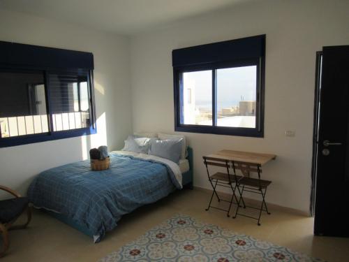 OvnatUnique&Warmy place in the Dead Sea的一间卧室配有一张床、一张桌子和两个窗户