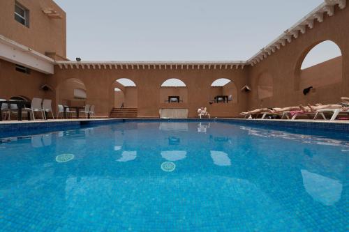 阿尤恩Hotel Al Massira的大楼里的一个大型蓝色游泳池