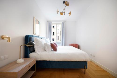 米兰numa I Loreto Apartments的卧室配有蓝色和白色的床和一张桌子