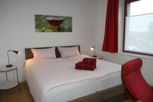 瓦尔堡FAMOS Schlafen的卧室配有白色的床和红色椅子