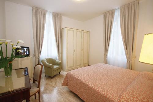 瓦拉泽Hotel Villa Elena的一间卧室配有一张床、一把椅子和电视