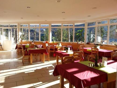 克拉尼斯卡戈拉Rooms Barovc by the Lake Jasna的餐厅设有红色的桌椅和窗户。