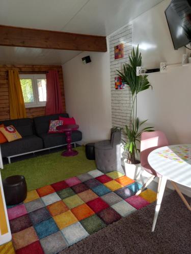 OisselBungalow la Bohémienne的客厅配有沙发和色彩缤纷的地毯