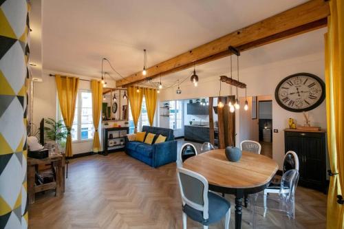 尚蒂伊La Suite de Chantilly - Appartement de 80m2 avec Jacuzzi privé !的客厅配有桌子和墙上的时钟