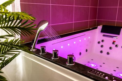 谢西LoveSparadise - Suite L'élixir的浴室内设有一个紫色照明浴缸