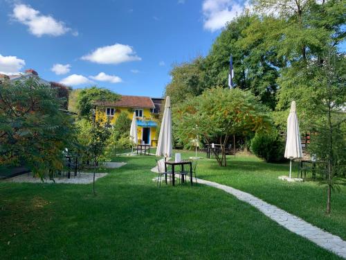 斯勒尼克Pensiunea Deceneu的草地上带桌子和遮阳伞的花园