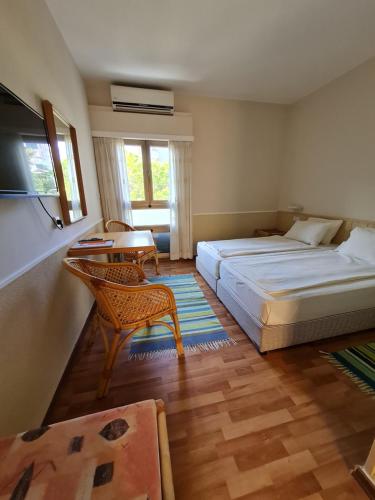 海法伯沙洛姆酒店的一间卧室配有两张床、一张桌子和一把椅子