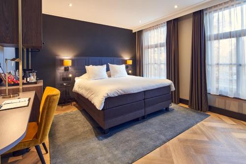 维格尔The Yard hotel Zuidkade的酒店客房配有一张床、一张书桌和一张书桌。
