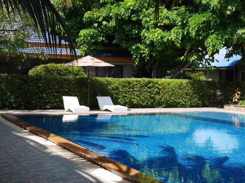皮皮岛Andaman Resort的一个带两把椅子和遮阳伞的游泳池