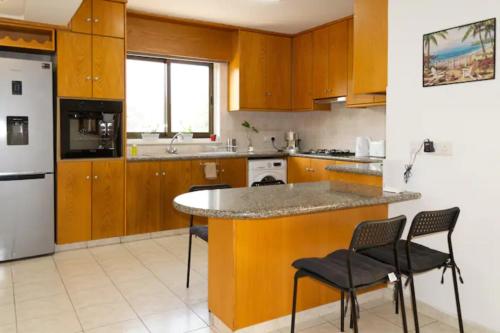 利马索尔Guest Apartments的厨房配有木制橱柜和带椅子的柜台。