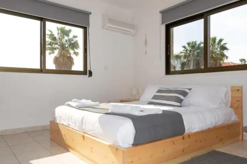 利马索尔Guest Apartments的一间卧室配有木床和2个窗户