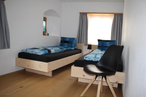 米施泰尔Chasa Allegra Müstair的一间卧室配有两张床和椅子