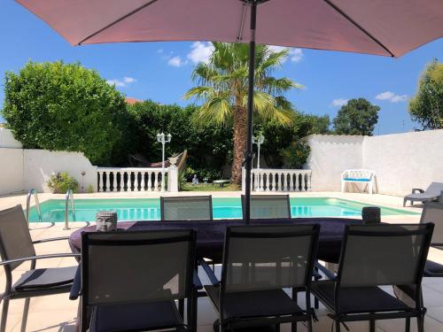 贝济耶Villa du sud ouest的游泳池旁配有桌椅和遮阳伞