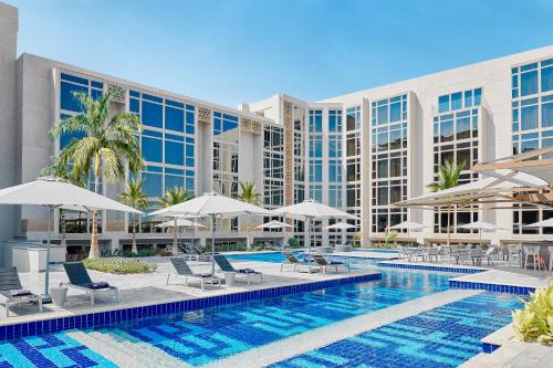 十月六日城Hyatt Regency Cairo West的酒店前方的游泳池配有椅子和遮阳伞