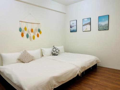 花莲市水上雅居民宿的一间白色的卧室,配有一张床和墙上的一些照片