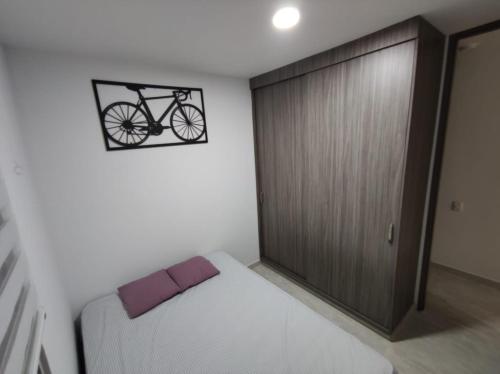 比亚维森西奥Encantador y acogedor apto amoblado villavicencio的卧室配有一张床,墙上挂着自行车