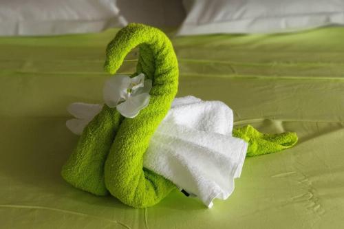 勒拉芒坦Le Lis Vacances et Affaire Cosy vue Mer的床上的绿毛巾和鲜花