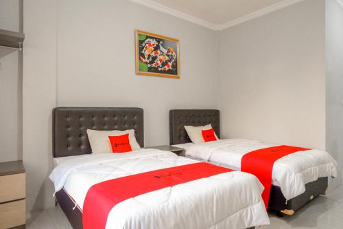 梭罗RedDoorz near Jalan Adi Sucipto Solo的配有红色和白色床单的客房内的两张床